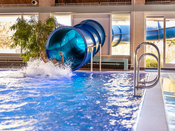 De grote, blauwe tunnelglijbaan in het overdekte zwembad van Vakantiepark Aquadelta zorgt voor een spetterend einde in het water.