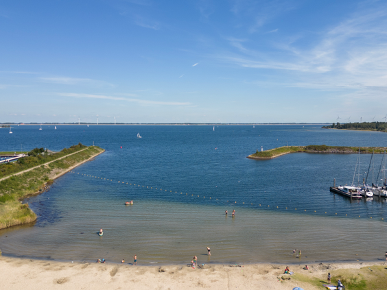 Het strand en het heldere water van het Grevelingenmeer, direct gelegen bij Vakantiepark Aquadelta in Zeeland.