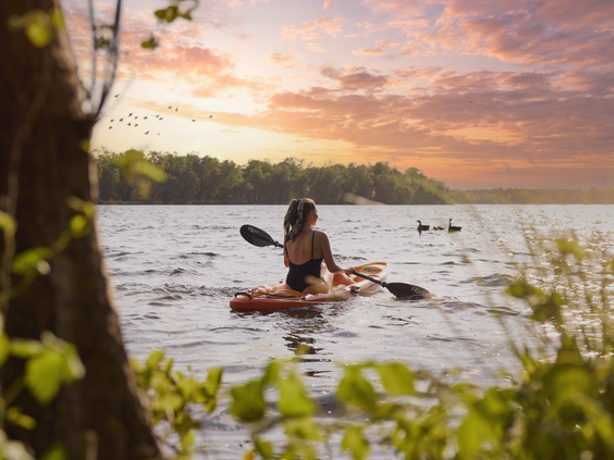 Vrouw in een kajak op het Victoriameer bij Beekse Bergen tijdens een prachtige zonsondergang