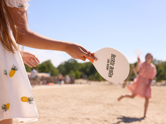 Kinderen spelen een potje beachtennis op het zonnige strand van Vakantiepark Beekse Bergen.