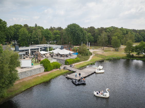 Luchtfoto van Vakantiepark Bospark 't Wolfsven in Noord-Brabant, met een jachthaven aan het recreatiemeer, bootjes en omringende bossen.