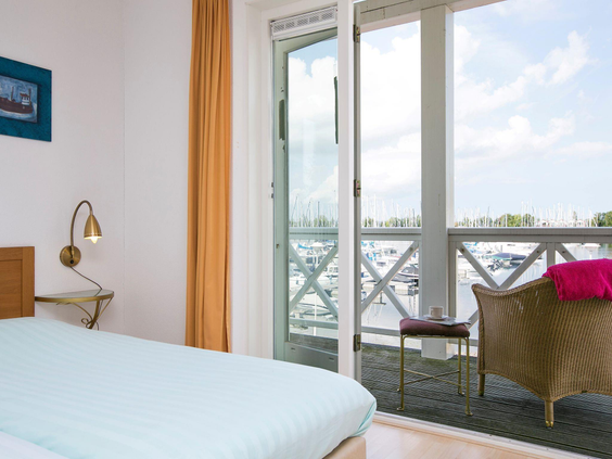 Slaapkamer in een appartement op Cape Helius met openslaande deuren naar het balkon en uitzicht op de jachthaven.
