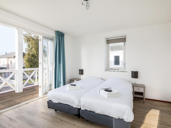 Een lichte, ruime slaapkamer met een comfortabel tweepersoonsbed en toegang tot het balkon in een accommodatie op Cape Helius.