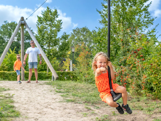 Een meisje aan de kabelbaan zipline in de speeltuin van de camping
