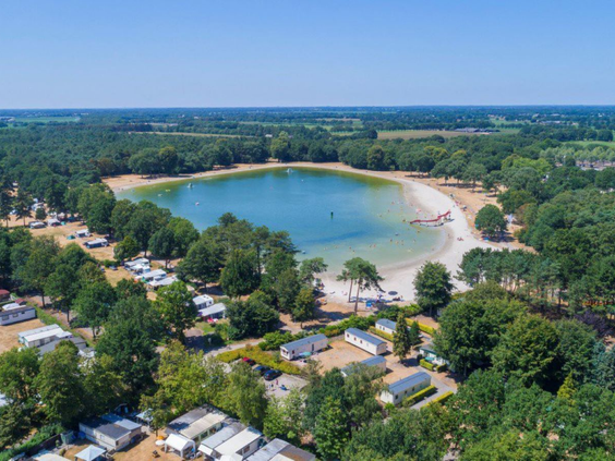Luchtfoto van Vakantiepark De Bergen in Wanroij, met een grote recreatieplas omgeven door bos en kampeerplaatsen.