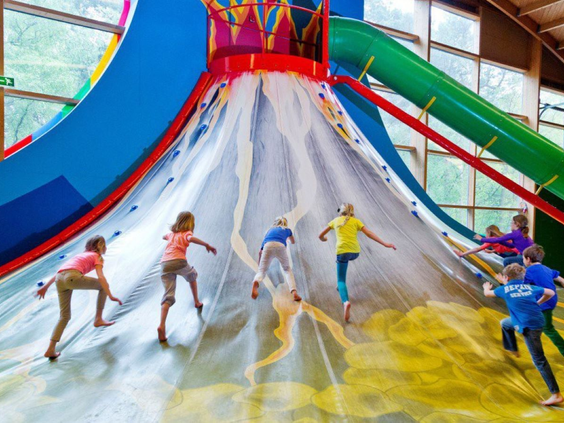 Kinderen proberen de top te bereiken van de grote klimvulkaan in de binnenspeeltuin van Vakantiepark De Bergen.