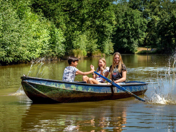 Gezin met kinderen geniet van een boottocht in een roeiboot op de recreatieplas van Vakantiepark De Bergen.