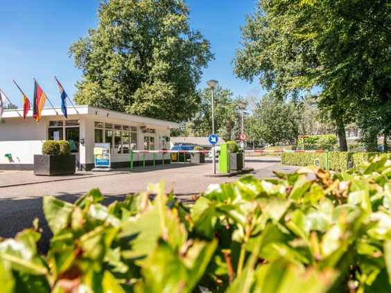 De ingang en het centrumgebouw van Vakantiepark De Bergen op een zonnige dag.