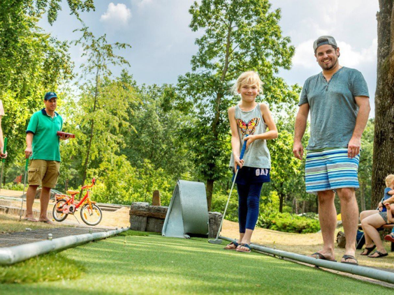 Gezin speelt een potje midgetgolf op de avontuurlijke midgetgolfbaan van Vakantiepark De Bergen.