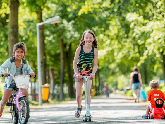 Kinderen fietsen en steppen vrolijk over de paden van het groene en ruime Vakantiepark De Bergen.
