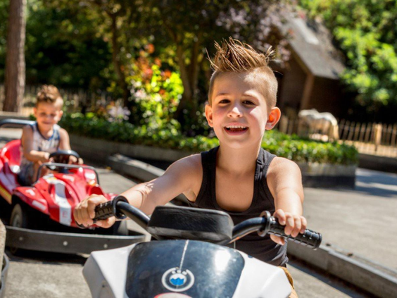 Lachende jongen rijdt in een elektrische minicar op de speciale kinderbaan van Vakantiepark De Bergen.