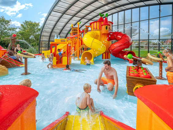 De overdekte waterspeeltuin met kleurrijke sproeiers en glijbanen