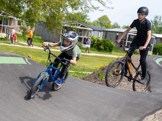 Kinderen crossen op hun fiets over de golvende pumptrack baan