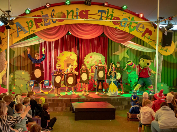 Kinderen kijken ademloos naar een voorstelling in het theater van de camping.