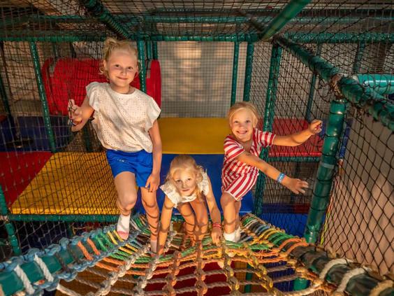 Kinderen klauteren veilig door de klimnetten in de binnenspeeltuin