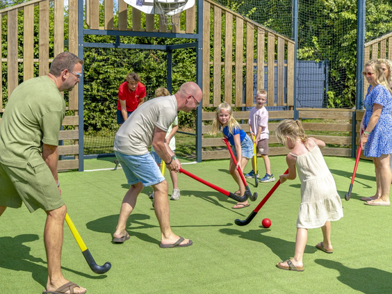 Familie speelt een potje hockey op de camping