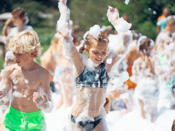 Kinderen onder het schuim tijdens een schuimparty op de camping