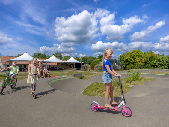 Meisje op een step op de geasfalteerde crossbaan van de camping