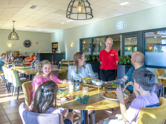 Gasten zitten op het terras van het campingrestaurant bij de Fruithof