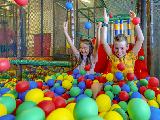 Lachende kinderen spelen in de ballenbak vol gekleurde ballen