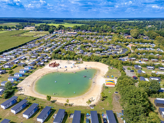 Grote luchtfoto van het hele vakantiepark met zwemvijver en faciliteiten