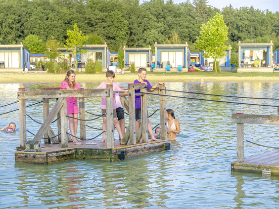 Kinderen op een houten trekvlot op de vijver van de camping