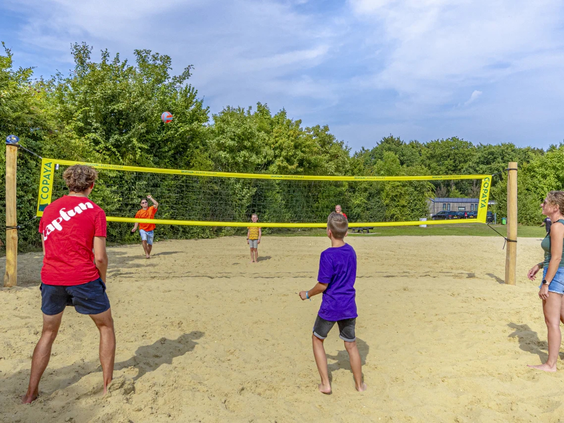 Mensen spelen volleybal op het beachvolleybalveld van de camping