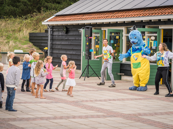 Kinderen dansen met mascotte Joris en het animatieteam tijdens de kinderdisco bij Vakantiepark De Krim op Texel.