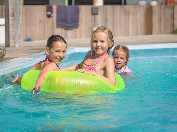 Drie meisjes spelen en lachen in een opblaasbare band in het buiten zwembad van Vakantiepark De Krim.