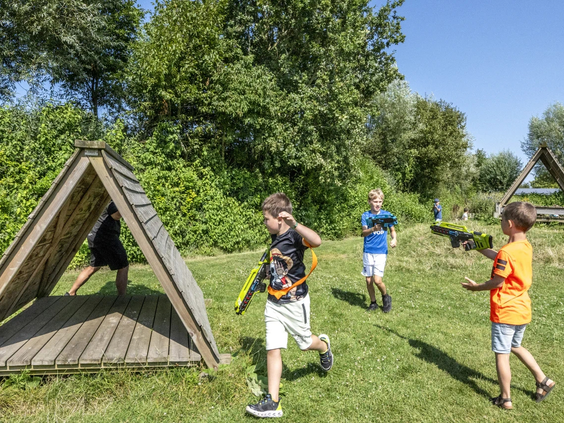 Kinderen rennen en spelen tussen de houten hutten in de natuurlijke omgeving van de camping