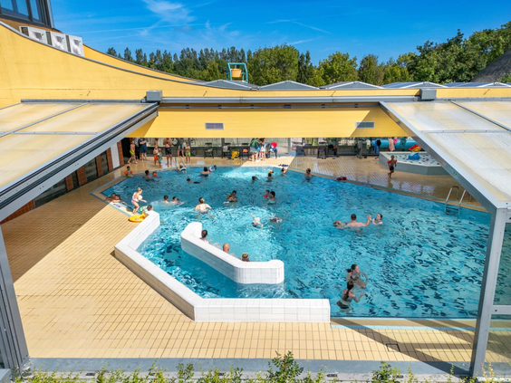 Het grote buitenzwembad van de Pekelinge met glijbanen en comfortabele ligbedden