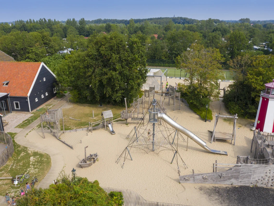 Luchtfoto van de grote speeltuin met houten speeltoestellen en zandbakken op de Pekelinge