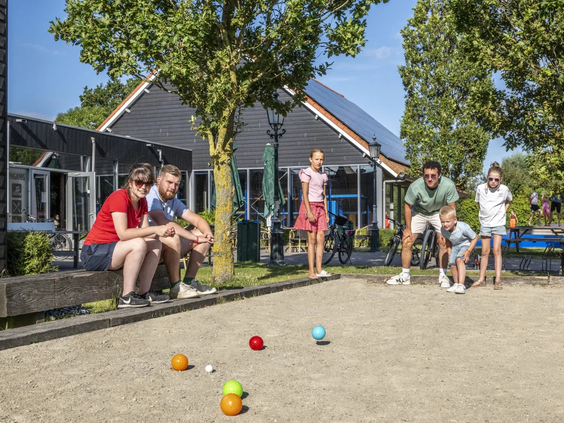 Gasten spelen een gezellig potje jeu de boules op de baan bij het terras