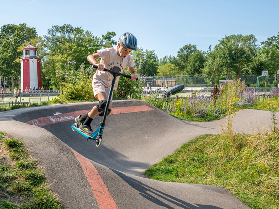 Kinderen rijden met hun step over de golvende pumptrack baan van de camping