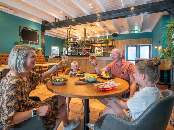 Een gezin geniet samen van een maaltijd in het sfeervolle restaurant op het park