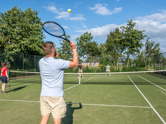 Mensen spelen een fanatiek potje tennis op de tennisbaan van camping de Pekelinge