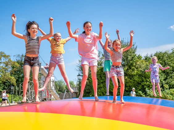 Kinderen springen samen op de grote vrolijk gekleurde air trampoline van de camping