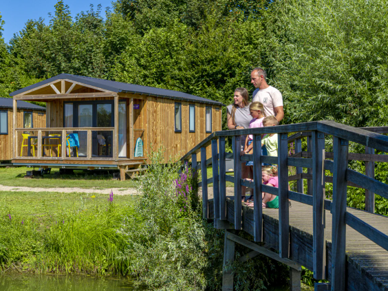 Een gezin loopt over een bruggetje naar hun moderne vakantiewoning