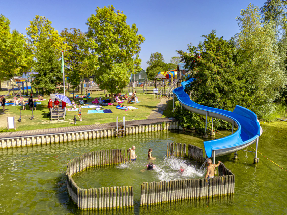 De grote blauwe glijbaan die direct uitkomt in het recreatiemeer