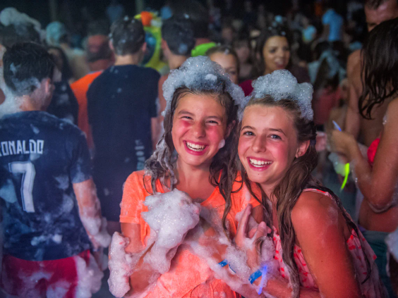 Lachende jongeren bedekt met wit schuim tijdens een schuimparty op de camping