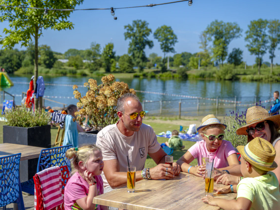 Een familie geniet samen van een maaltijd op het terras van het parkrestaurant