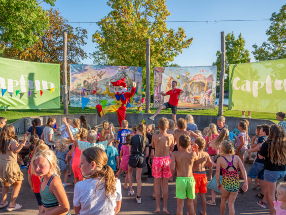Een grote groep kinderen danst buiten mee met het enthousiaste animatieteam