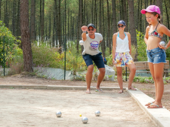 Gasten spelen een potje jeu de boules op de baan tussen de bomen