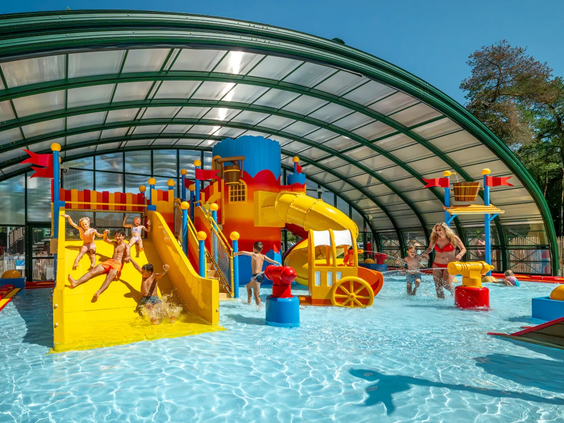 Het lichte binnenzwembad met glijbanen en waterspeeltoestellen