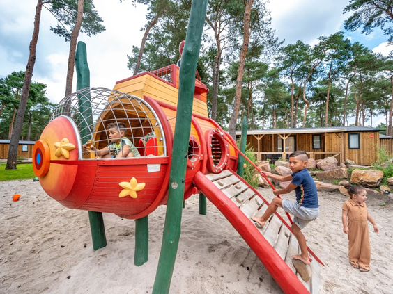 Close-up van een speeltoestel met een rode glijbaan op de camping
