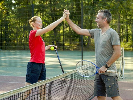 Mensen spelen een fanatiek potje tennis op de tennisbaan van de camping
