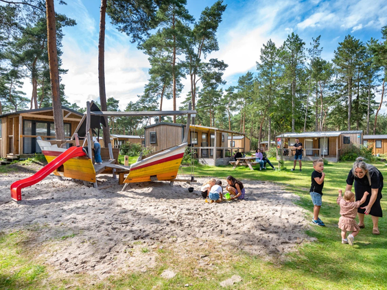 Houten speeltoestellen in een grote zandbak op de camping