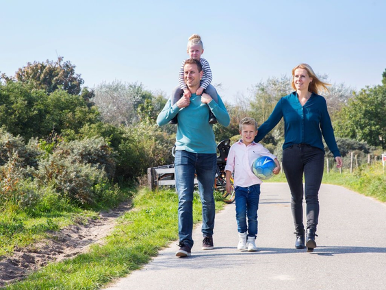 Een gezin met jonge kinderen wandelt over een pad door het prachtige duinlandschap van Renesse in Zeeland.