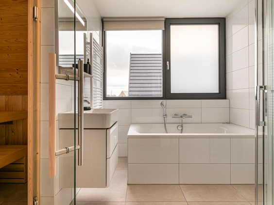 Een moderne wellness-badkamer met ligbad en uitzicht op de privé-sauna, in een luxe vakantiewoning op Vakantiepark De Strabrechtse Vennen.