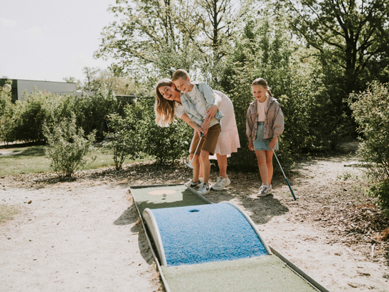 Een gezin speelt een potje midgetgolf op de avontuurlijke minigolfbaan van Vakantiepark Dierenbos.